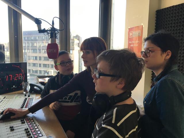 Die Gruppe der Jugendlichen zusammen mit der Moderatorin Julia Sermann am Mischpult des Studios.