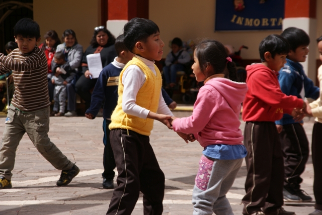 Kinder der Schule in Cusco tanzen gemeinsam auf dem Schulhof.